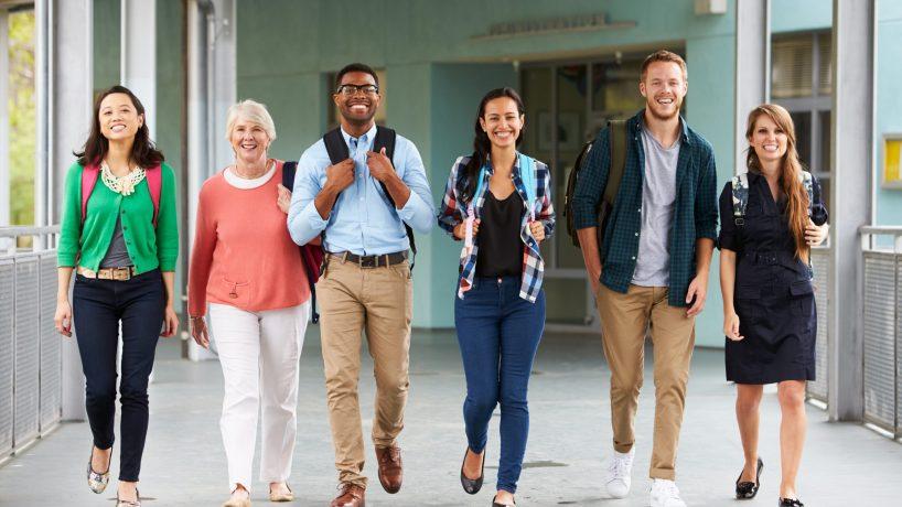 A group of happy teachers walking in a school corridor